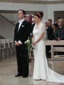 Das Brautpaar in der Kirche, er in Frack, sie in einem schmalen eleganten Brautkleid
